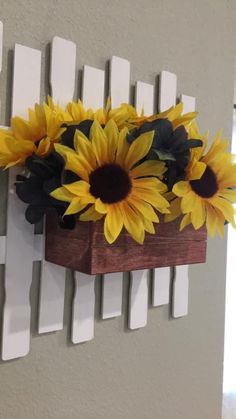 sunflowers are placed in a wooden box on the wall