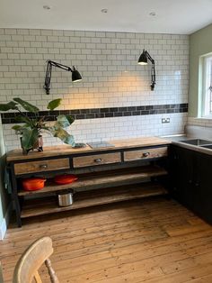 a kitchen with wooden flooring and white tiled walls, along with black cabinetry