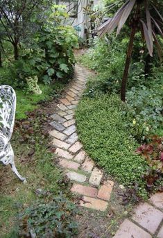 a white bench sitting in the middle of a lush green garden next to a house