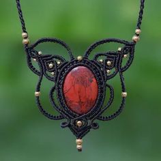 a red stone is attached to a black cord necklace with gold beads and beading