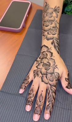 a woman's hand with hendix and flowers on it next to a tabletop