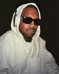 a man wearing sunglasses and a hoodie with headphones on his ears is looking off to the side