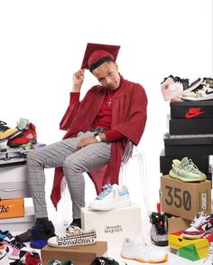 a man in a graduation cap and gown sitting on top of a pile of shoes