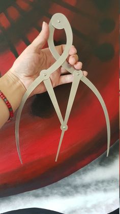 a pair of scissors that are on top of a surfboard in front of a woman's hand