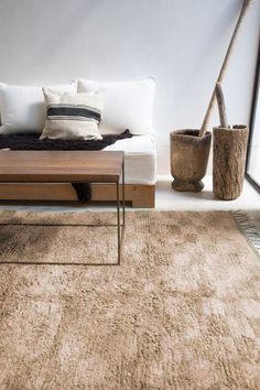 a living room with a couch, coffee table and vases on the floor in front of it