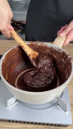 a person mixing chocolate in a bowl with a wooden spoon