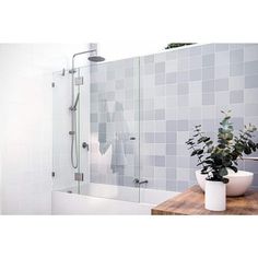 a bathroom with tiled walls and a plant on the counter in front of the shower