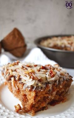 a piece of cake sitting on top of a white plate next to a bowl of nuts