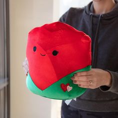 a woman is holding a red and green pillow