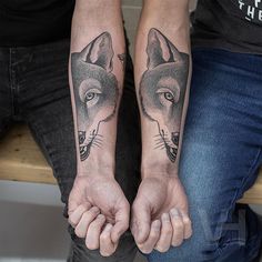 two people holding hands with tattoos on their arms and the other one has a wolf tattoo on it's arm