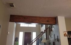 an open door leading to a living room and dining room with wood beams on the ceiling