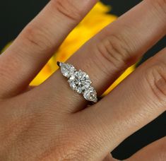 a woman's hand with a three stone diamond ring on top of her finger