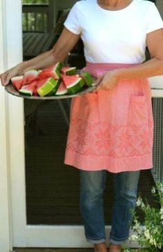 a woman holding a plate with slices of watermelon on it in front of a door