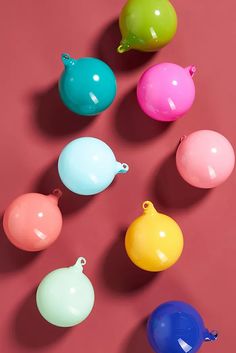 several different colored plastic ornaments on a pink surface