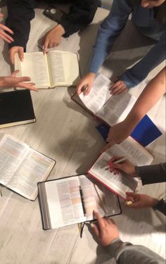 a group of people sitting at a table with open books in front of each other