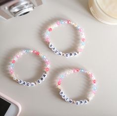 three personalized bracelets on a table next to a cell phone and camera lens