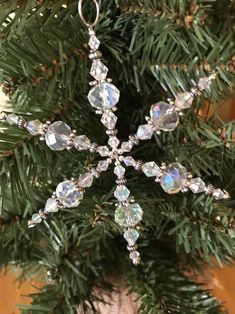 a snowflake ornament hanging from a christmas tree with clear crystal beads