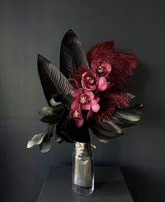 a vase filled with lots of flowers on top of a table next to a wall