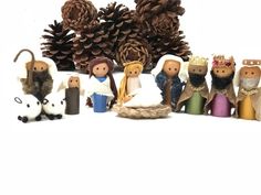 a group of small figurines sitting on top of a white surface next to pine cones