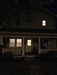 a house that is lit up at night with the lights on and two windows open