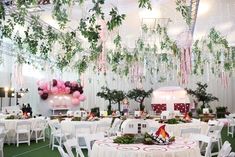 tables and chairs are set up for an event with balloons, greenery, and other decorations