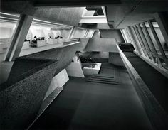 black and white photograph of the interior of an office building with concrete walls, flooring and windows