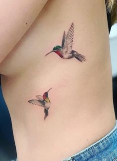 two hummingbirds flying next to each other on the side of a woman's stomach