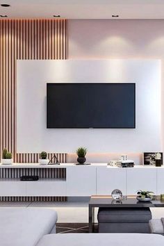 a living room with white furniture and a flat screen tv mounted on the wall above it