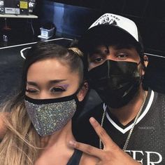 a man and woman wearing face masks posing for the camera