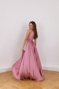 a woman in a long pink dress standing on the floor with her back to the camera