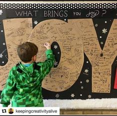 a young boy writing on a bulletin board with the words joy written on it and snowflakes