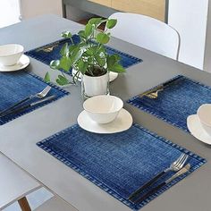 a table set with place mats, silverware and a potted plant on it