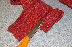 a pair of red gloves sitting on top of a bed next to a pair of scissors