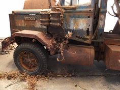 an old rusted truck sitting on the side of a road