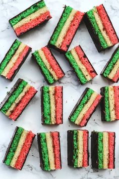 several pieces of cake with different colored frosting on top of marble countertop next to each other