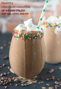 two glasses filled with chocolate milkshakes and sprinkles on a table