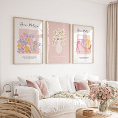 a living room filled with white furniture and pink flowers on the wall next to a window