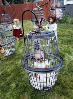 two dolls are sitting in small cages on the grass