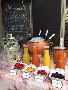 a table topped with lots of different types of food next to bottles of juice and glasses