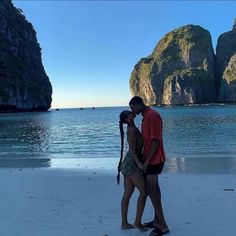 two people kissing on the beach with mountains in the background