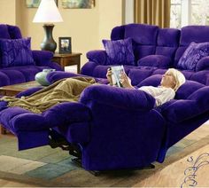 a woman laying on a purple couch in a living room next to a blue recliner