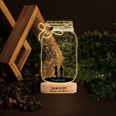 a mason jar with a couple holding hands under a star filled sky on top of a wooden stand