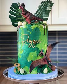 a dinosaur themed birthday cake with green frosting and leaves on the top, sitting on a blue plate