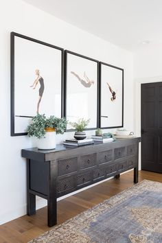 a living room with three framed pictures on the wall and two vases filled with flowers