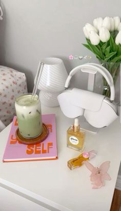 a white table topped with a vase filled with flowers next to a candle and other items