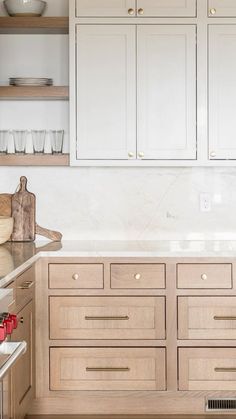 a kitchen with wooden cabinets and white counter tops, along with dishes on the shelves