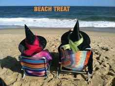 two lawn chairs on the beach facing the ocean with hats on their heads and one chair covered in blankets