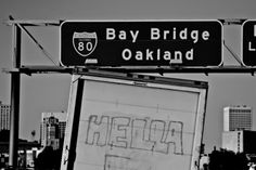 black and white photograph of the bay bridge sign in oakland, with graffiti on it