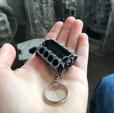 a hand holding a black and silver object in it's right hand, with the key chain attached to it