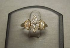 an engagement ring in a glass case with a diamond on the top and side stones